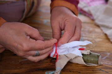 A woman makes a toy baby doll in the retro style of the Middle Ages. Medieval life and the creation of simple toys for children