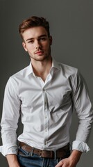 Man in a white dress shirt and jeans poses against a gray background