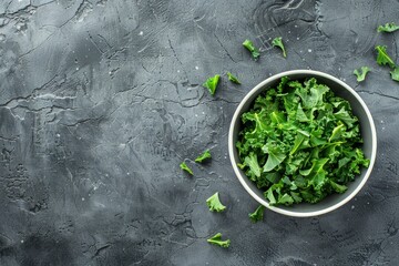 Bowl of fresh green chopped kale on gray rustic stone background, top view, close-up. Ingredient for making healthy salad. Clean eating, detox or diet concept