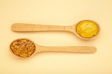 Different mustard in spoon on beige background with clipping path.