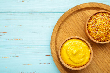 Dijon mustard with french mustard on blue wooden background.