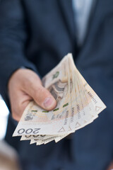 Osoba trzymająca w dłoni banknoty pieniężne, Polskie Złote. 