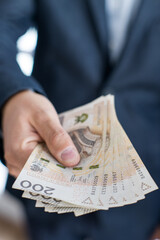 Osoba trzymająca w dłoni banknoty pieniężne, Polskie Złote. 