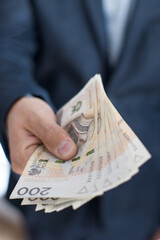 Osoba trzymająca w dłoni banknoty pieniężne, Polskie Złote. 