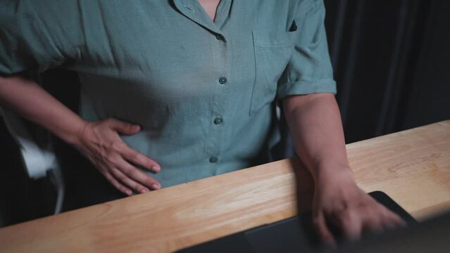Close up - Hand woman worked so hard that her stomach hurt. Got office syndrome after working on a laptop computer at home, Working on the notebook at night, period pain