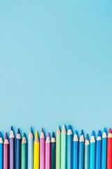 A row of colorful crayons on a light blue background 