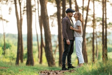 Fototapeta premium Looking at each other. Lovely couple are together in the forest at summer daytime