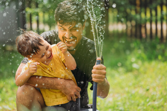 Father and son spending leisure time splashing water in garden