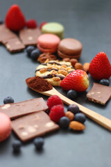 Macarons, chocolate, cookies, berries and various nuts on dark blue background. Selective focus.