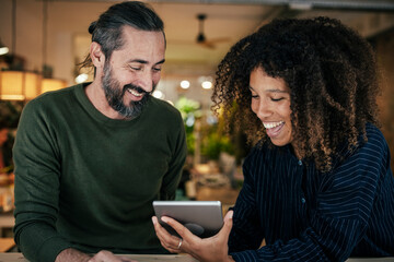 Cheerful colleagues using tablet PC at cafe