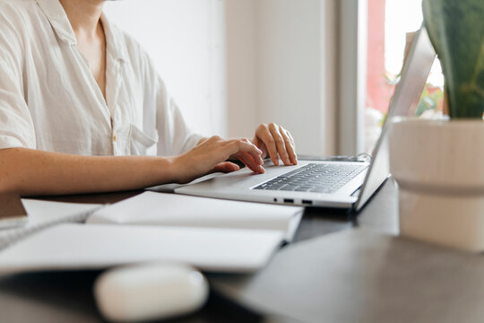 Freelancer scrolling laptop at desk in home office