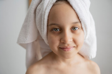 Smiling girl with towel wrapped on head after shower at home