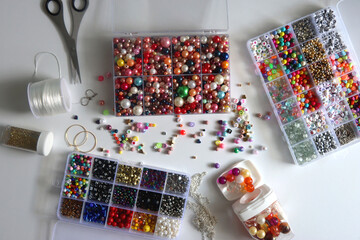 Colorful beads, letter beads, threads and other jewelry making supplies on white background. Making friendship bracelets concept. Flat lay.