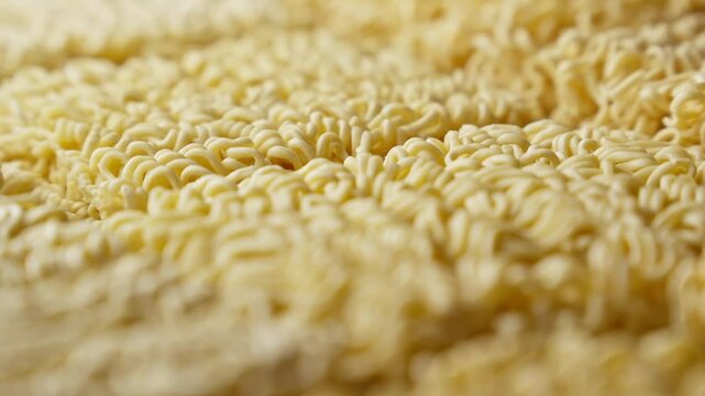 Dried ramen noodles rotating. Instant noodles. Dried uncooked asian instant noodles. Noodles are yellow color and have wavy texture. Close together and very dry. Close-up in 4K, UHD