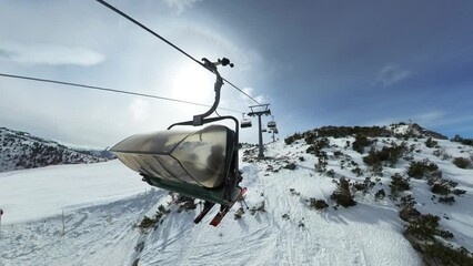 Following shot of a chair lift shot from behind with fish eye during winter in the austrian Alps