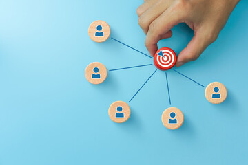 Businessman hand holding target icon on red wooden cube and wooden cubes with person icons. Target...