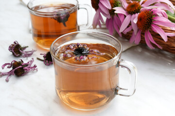 Homemade herbal tea. A remedy that boosts immunity and relieves stress. Glass cups and tea with a hot healthy drink. Transparent jars with dried echinacea flowers. Side view. 