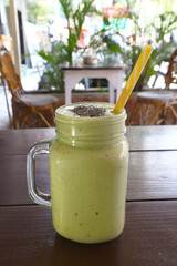 Avocado smoothie with banana and flaxseed in a jar with a straw. Vegetarian light breakfast. Vertical photo.