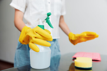 Two women cleaning together one in yellow gloves with a spray bottle, the other holding a sponge