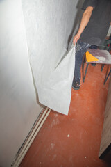 Caucasian worker applying wallpaper to wall at home.