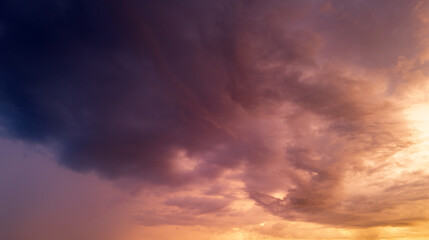 Beautiful sunset sky with clouds. Sky blue and orange light of the sun through the clouds in sky. Background of dark clouds before storm. Dramatic clouds. Apocalyptic sky, dark cloud.