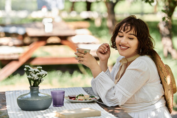 A beautiful brunette enjoys a leisurely brunch in a sunny garden, dressed in a white dress.