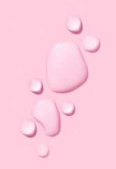 round drops of transparent gel serum on pink background