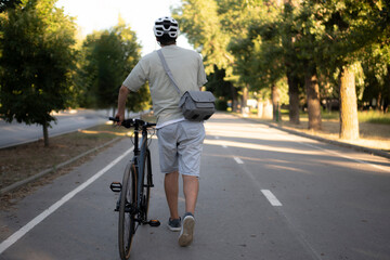 bicycle courier rides on a bike path in the city, wearing a helmet and carrying a small delivery bag