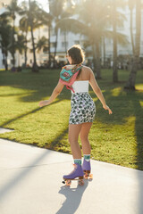 A young woman in sunglasses and stylish attire skates on a sidewalk under palm trees in Miami.