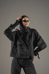 Fototapeta premium Young fashionable girl in a business suit posing on a gray background.