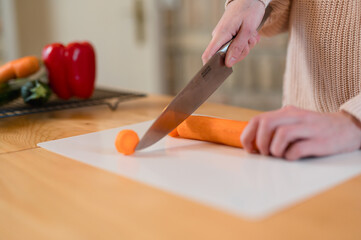 Obraz premium Girl holding and slicing carrot for healthy meal 