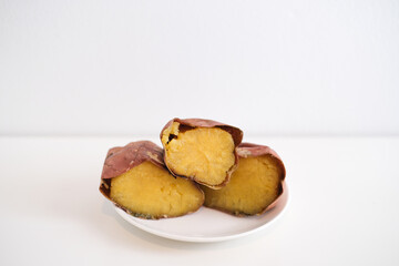 Japanese autumn taste, roasted sweet potato.roasted sweet potatoes broken in half on a white background on a plate.
