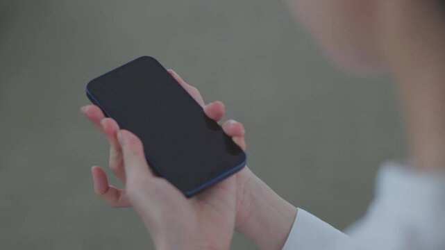 スマートフォンにSIMカードを差し込む日本人女性の手元