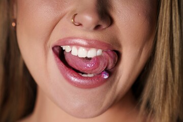 Close-up of a girl with a tongue piercing and a nose ring, showing her teeth and tongue