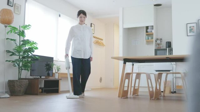 リビングにて掃除機をかける日本人女性