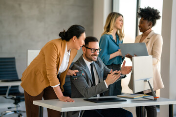 Happy businesspeople laughing while collaborating on a new project in an office.
