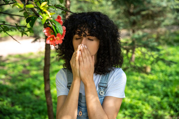 Dark-haired young woman sneezing and feeling unwell, having allergy symptoms