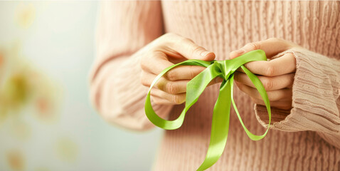 Close-up of hands holding a green ribbon, a symbol of mental health awareness