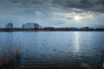 The sun behind rainy clouds over the lake