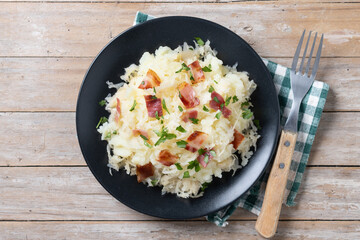 Slovak potato dumplings halusky with steamed sauerkraut and bacon on wooden table