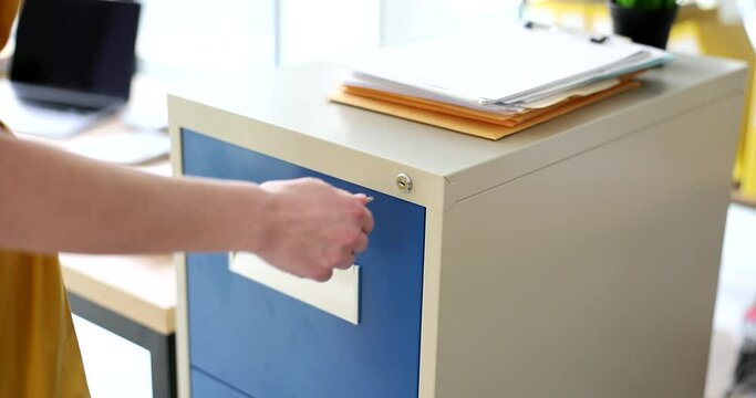 Hand of woman turns key to lock safe with valuable documents. Female employee closes drawer with safety lock in office slow motion