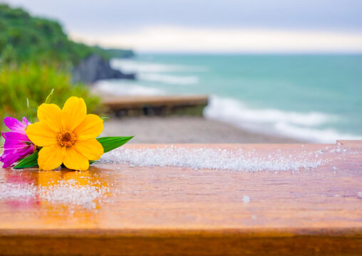 Yellow and Purple Flowers on a Wooden Surface with a Sea Background. - Powered by Adobe