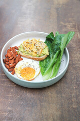 bread with egg and avocado topping with sunny side up egg , lettuce and almond