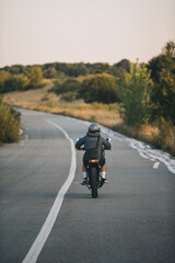 A biker rides a cafe racer on the highway