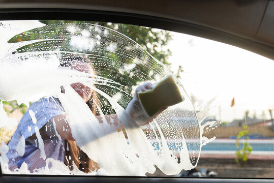 Washing a car window with soapy sponge from inside view