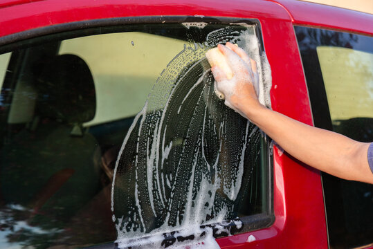 Hand washing a red car with soapy water