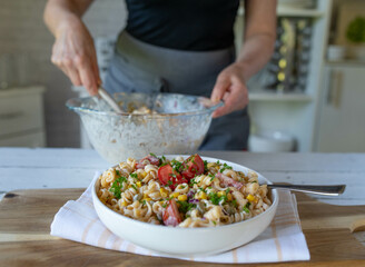 Homemade food. Woman with apron preparing a fresh pasta salad