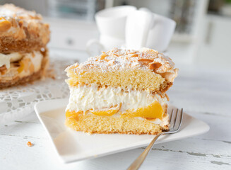 Peach cake or torte with whipped cream filling and meringue topping on a plate.