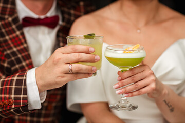 The bride and groom clink glasses with a delicious cocktail