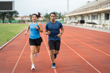 Obraz premium Asia mature woman and man runner training on racetrack and field 
